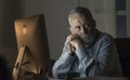 Pensive senior man working with his computer at night Royalty Free Stock Photo