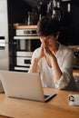 Senior woman working on laptop computer while sitting in kitchen Royalty Free Stock Photo