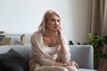 Pensive senior woman look in distance yearning at home