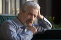 Pensive serious elderly man thinking sitting on couch