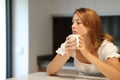 Pensive serious woman holding mug at home