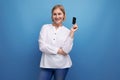 pensive slim blondie middle-aged woman in a white blouse holding a plastic card for shopping Royalty Free Stock Photo