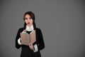 Pensive smart young girl student in gothic black clothes with pigtails with book, got idea and look at empty space