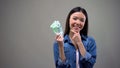 Pensive smiling woman holding euros, isolated on grey background, cashback