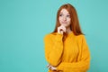 Pensive smirked young redhead woman girl in yellow sweater posing isolated on blue turquoise wall background. People Royalty Free Stock Photo