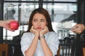 Pensive stressed Asian woman choosing between apple or unhealthy cake on the desk. Healthy lifestyle and dieting concept. Selecti Royalty Free Stock Photo