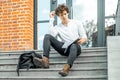 Pensive student sitting on modern building steps and making notes in notepad Royalty Free Stock Photo