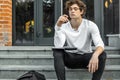 Pensive student sitting on modern building steps and making notes in notepad Royalty Free Stock Photo