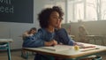 Pensive student sitting at school desk in class. Female pupil learning science