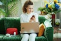 Woman buying pharma using laptop at modern home in sunny day