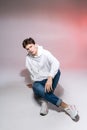 Pensive teen boy posing sitting on the floor in the studio. Portrait of stylishly dressed student. Studio shot Handsome Royalty Free Stock Photo