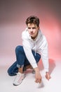 Pensive teen boy posing sitting on the floor in the studio. Portrait of stylishly dressed student. Studio shot Handsome attractive Royalty Free Stock Photo