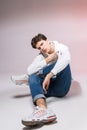Pensive teen boy posing sitting on the floor in the studio. Portrait of stylishly dressed student. Studio shot Handsome attractive Royalty Free Stock Photo