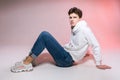 Pensive teen boy posing sitting on the floor in the studio. Portrait of stylishly dressed student. Studio shot Handsome attractive Royalty Free Stock Photo