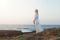 Pensive teenager girl in white dress standing on the beach looking away at the horizon in the morning Royalty Free Stock Photo