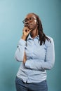 Pensive thoughtful african american woman being meditative and introspective on blue background. Royalty Free Stock Photo