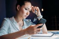 Pensive tired asian businesswoman holding eyeglasses and using smartphone Royalty Free Stock Photo