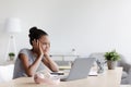Pensive tired bored adolescent afro american girl studying remotely, rest from lesson and looking at laptop Royalty Free Stock Photo
