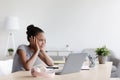 Pensive tired bored adolescent afro american girl studying remotely, rest from lesson and looking at laptop