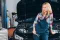 Pensive tired woman in uniform looking aside while standing in front of the car Royalty Free Stock Photo