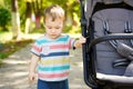 Pensive toddler boy stands near the stroller in the park. Cute kid of one and a half years. Selective focus Royalty Free Stock Photo