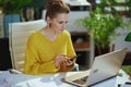 pensive trendy business owner woman in green office using phone Royalty Free Stock Photo