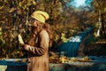 pensive trendy woman in brown coat and yellow hat