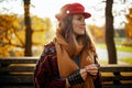 pensive trendy woman in red hat with autumn leaf