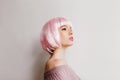 Pensive white woman with pink hair looking away. Indoor portrait of adorable girl in periwig posing in studio with