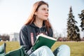 Pensive woman in earphones sitting and writing in notebook Royalty Free Stock Photo