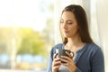 Pensive woman holding mug at home