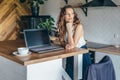 Pensive woman in the kitchen at the table with a laptop Royalty Free Stock Photo