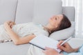 Pensive woman lying on the couch while psychologist writing Royalty Free Stock Photo