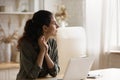 Pensive woman sit in kitchen with laptop looks into distance Royalty Free Stock Photo