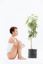 Pensive woman sitting and thinking near small tree in pot Royalty Free Stock Photo