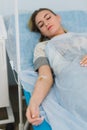 Pensive woman transfused lying in hospital ward