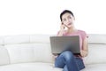 Pensive woman uses laptop on couch Royalty Free Stock Photo