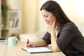 Pensive woman writing in a notebook at home Royalty Free Stock Photo