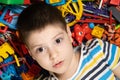 A pensive 5-year-old boy thinks while looking away while lying among scattered toys. Logic and development for Royalty Free Stock Photo