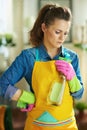 Pensive 40 years old housewife with cleaning agent and sponge