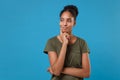 Pensive young african american woman girl in casual t-shirt posing isolated on blue background studio portrait. People Royalty Free Stock Photo