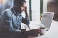 Pensive young African man reading financical news on laptop while drinking black coffee in sunny morning.Concept of Royalty Free Stock Photo