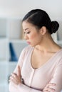 Pensive young asian woman standing with crossed arms and looking down Royalty Free Stock Photo