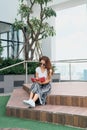 A pensive young asian woman writing in notebook while sitting outdoors on staircase Royalty Free Stock Photo