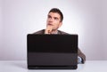 Pensive young business man behind laptop looks away Royalty Free Stock Photo