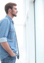 Pensive young businessman looking through office window. Royalty Free Stock Photo