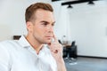 Pensive young businessman sitting and thinking in office Royalty Free Stock Photo