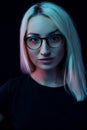 Pensive young Caucasian beautiful blonde woman with glasses . close-up portrait in neon light Royalty Free Stock Photo