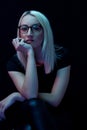 Pensive young Caucasian beautiful blonde woman with glasses . close-up portrait in neon light Royalty Free Stock Photo