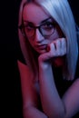 Pensive young Caucasian beautiful blonde woman with glasses . close-up portrait in neon light Royalty Free Stock Photo